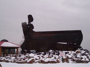 The giant bucket is hinged with a mouth that opens to scoop up ore.
The visitor building in the background is dwarfed by the bucket, sitting on 
a snowy hill.