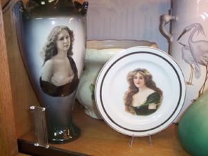 Paintings of girls with deep decolletage adorn a vase and a plate.