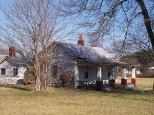 Small white fram home with wide front porch supported by wooden posts on 
brick foundations; two chimneys.