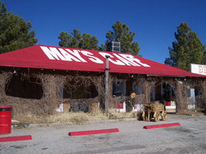 MAY'S CAFE is written in big white letters on the white red roof.  The
veranda is covered with vines.