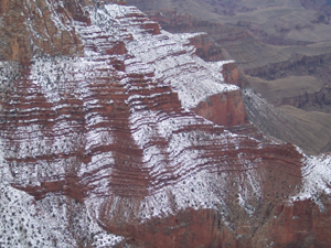 The reddish rock walls of the grand canyon covered with a light dusting
of snow reveal the thousands of strata.