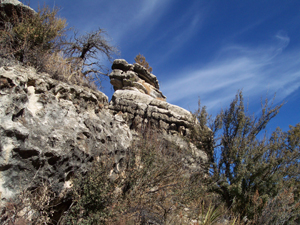 The bright blue sky is traced with fine thin clouds, in contrast with
the grey rock and dark green desert shrubs