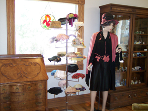View inside Overland Museum, showing beautiful wooden secretary and rack of 1930s hats
with mannequin wearing pink and black outfit