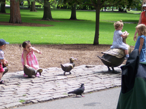 Children playing on bronze ducklings patterned after illustrations from McCloskey's book