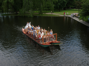 A swanboat full of riders on the lake in Boston Garden