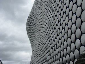 Against a cloudy sky, the side of the Selfridge's store in the Bullring is a striking piece of modern architecture; the curving lines of metal circles appear to disappear into the sky