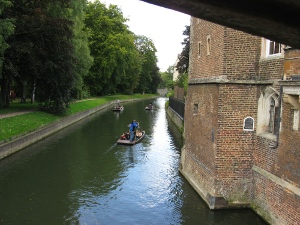 The river Cam runs in an orderly channel, fronting college buildings and retaining walls, and peopled by punters.