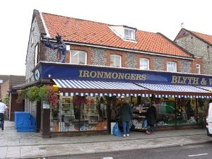 The shop has a blue canopy, labeled Ironmongers, and on top of the canopy a large blue statue of a lobster beckons tourists
