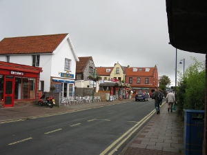 The roof of the bus shelter can be seen to the right, across a street with white and red houses and shops