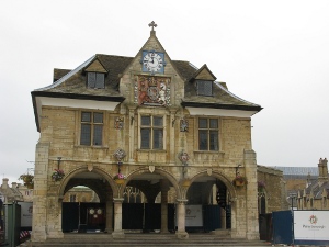 Three large arches, front and back, make the ground floor of the guildhall an open space; above is a floor with three windows, and above that a dormered roof with the royal coat of arms and the town clock.