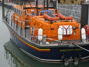Bright orange and made for rough seas, the lifeboat is tied up at the pier, ready to depart
