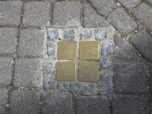 four small brass plaques are set in the sidewalk in commemoration of Jews killed by the Nazis