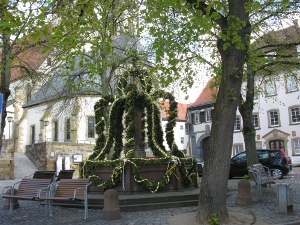 in the middle of a small plaza, the town fountain has been festooned with garlands of green, decorated with ropes of easter eggs.