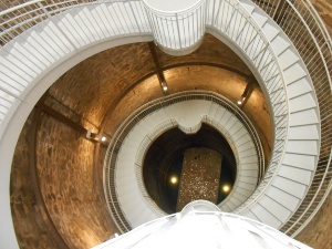 The painted white metal staircase spirals down the perimeter of the big stone well to the bottom, where a few coins from visitors have fallen