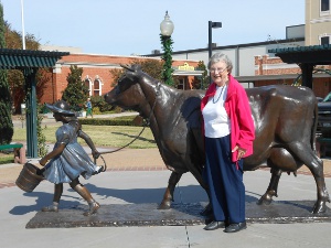 Elsa stands in front of the statue of the dairy cow in front of the Blue Bell Creamery.