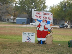 Santa is holding a sign reading Vesely Vanoce A Stastny Novy Rok (Merry Christmas and Happy New Year)