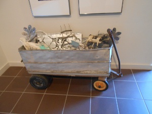 The handmade gray painted wagon is filled with metal flowers and other folk sculpture