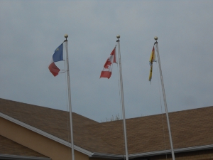 Three flagpoles with the flags of Acadia, Canada, New Brunswick on display