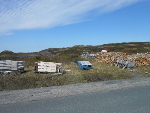 piles of wood are stacked along the roadside next to wooden sleds for carrying it