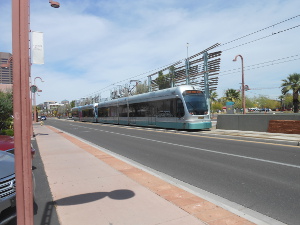 The sleek silver train, consisting of two double-length articulated cars, with huge view windows is parked in a modern station.