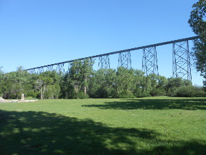 High above the grassy and wooded valley, the railroad bridge is perched atop massive iron lattice towers