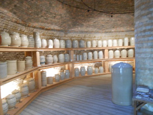 the inside of a kiln are lined with shelves of utilitarian cream-colored crockery in various sizes for sale to farms and ranches.