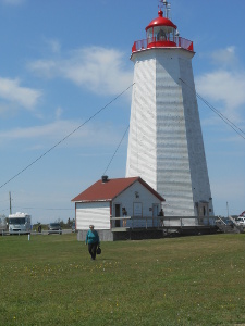 Elsa appears dwarfed in front of the tall white and red lighthouse.