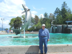 Bob stands next to the shiny metal salmon statue in the center of a wide circular pool
