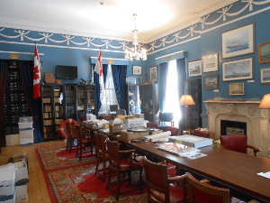 With blue walls, Persian carpets, a long conference table, pictures on the wall above a large fireplace, bookcases lining the other walls, and naval flags on display, the Conference Room is a busy place.
