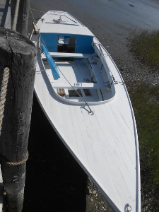 The bluish-gray boat has a sharp bow and stern and a working size central compartment with two thwarts and oars