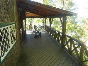 The wooden cabin is hand-crafted and decorated with a railing and Adirondack chairs.