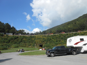 The grassy bank slopes up to the inside loop of the Horseshoe curve where a train is descending past the track workers