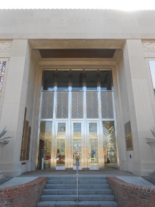 The very tall steel doors are dwarfed within a majestic entry in glass and more steel, surrounded by stone.