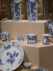 This display case features blue and white porcelain tea caddies and oil bottles and plates.