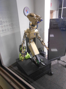 The copper-colored robot has gripper hands and a vaguely humanoid shape.
