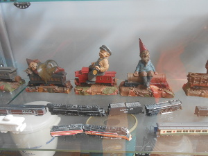 Carved and painted wooden figures sit astride model train cars