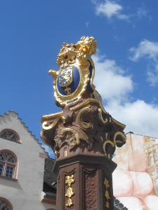 Atop a brown stone pillar highlighted in gold paint, the crest of Wiesbaden is displayed in blue and gold.