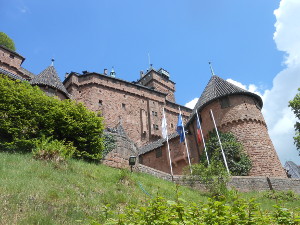 Looking up from below, the sides of the red stone castle stretch up to the sky
