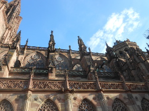against a light blue sky, the spires and red stone tracery of the cathedral make a delicate contrast