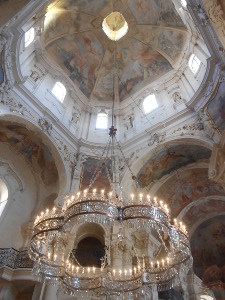 A beautiful chandelier is suspended beneath the dome lit by high windows and beautifully painted