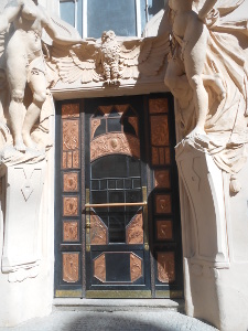 surrounded by life size statues, the black and brown door sits in a recess and is carved in lovely panels