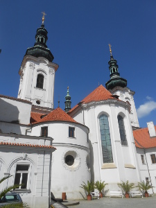 The photo shows the white walls of the monastery and towers capped with red or black roofs