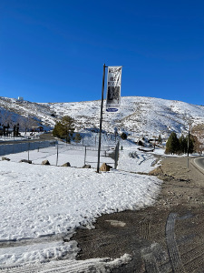 Hung from a tall steel pole above the snow-covered banks of Austin, Nevada (elevation 6575 feet, the words 'Social Distancing Since 1862' appear on the sign.