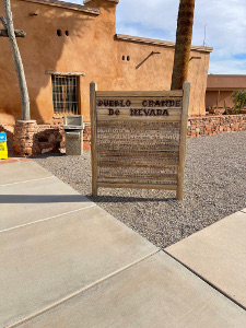 The wooden sign sits in front of the museum, built in pueblo-style architecture