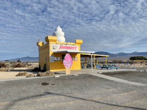 Surrounded by empty lots, Seemore's Ice Cream stand is painted yellow with a white cone built on the roof